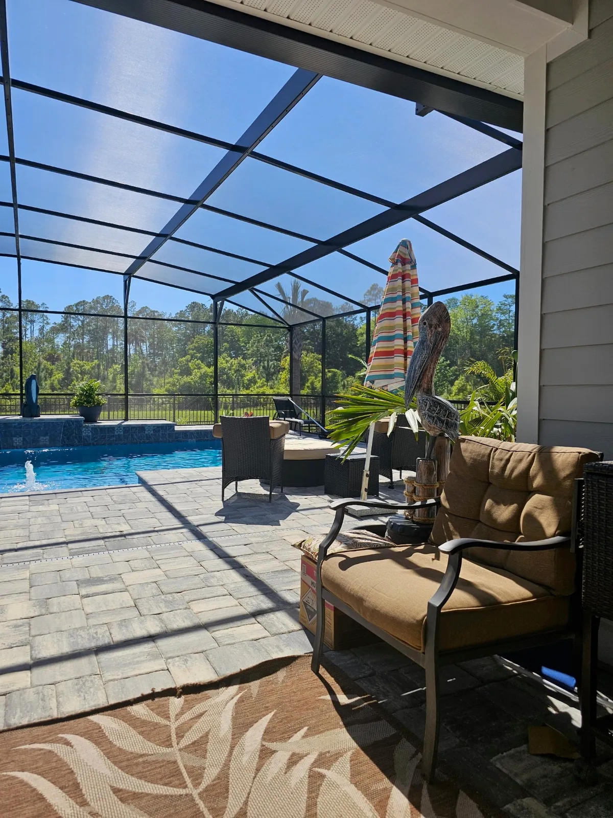 Covered lanai with cushioned seating overlooking a screen-enclosed pool