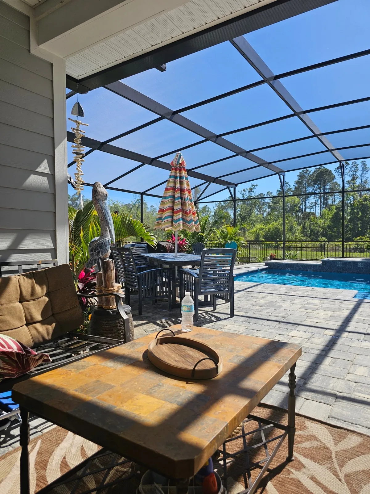 Poolside patio dining set and lounge seating under a screen enclosure