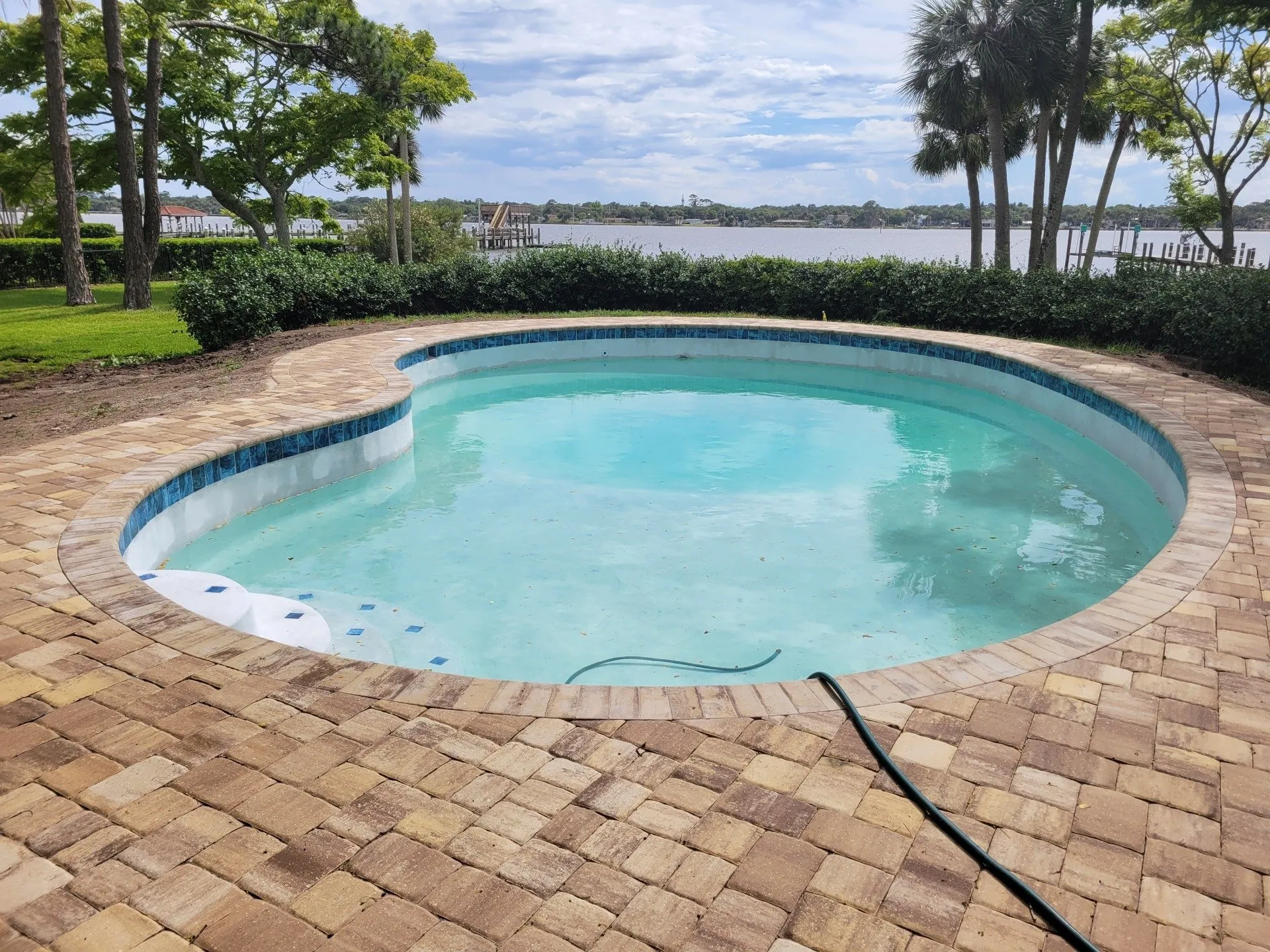 Freeform waterfront pool with paver deck overlooking the river