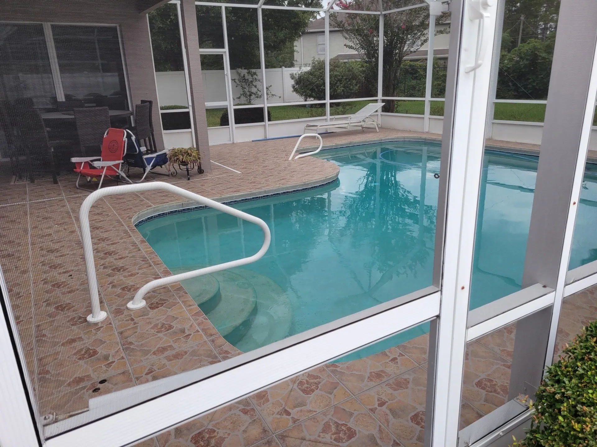 Screen-enclosed freeform pool with tiled deck