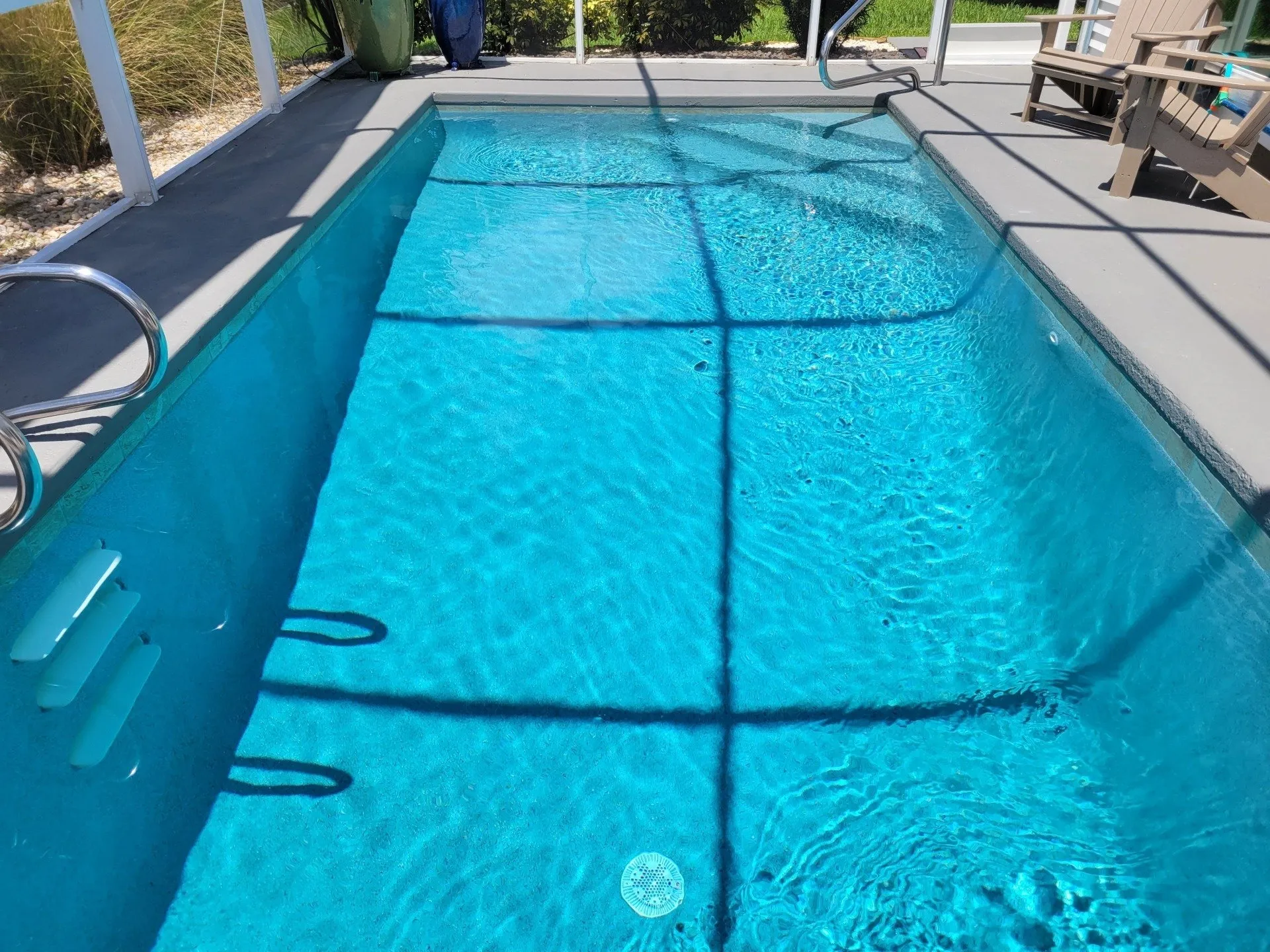Modern rectangular pool with bright blue water inside a screen enclosure