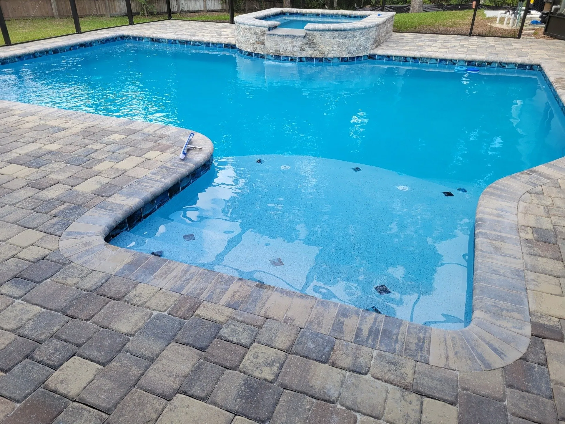 Custom pool with raised stone spa, spillover, and paver deck