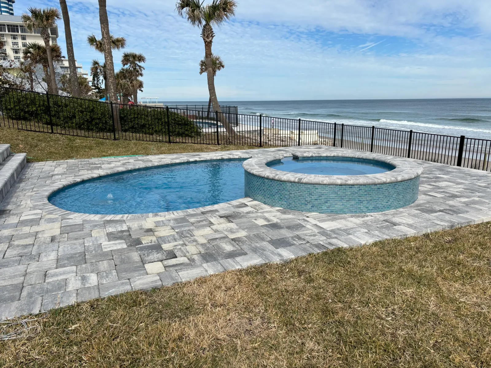 Freeform oceanfront pool and round spa with palm trees and ocean views