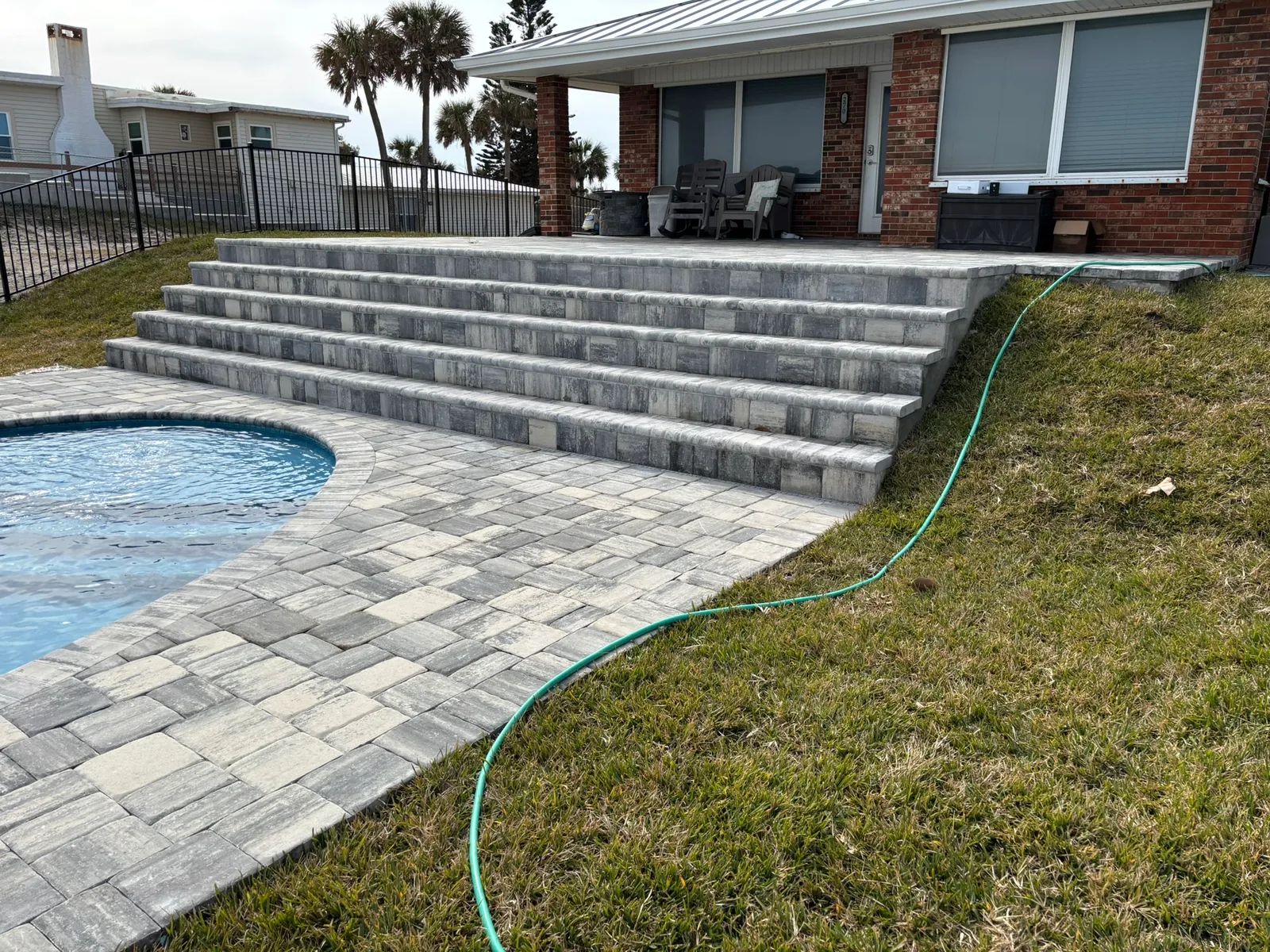 Gray paver deck and steps leading from the house down to an oceanfront pool